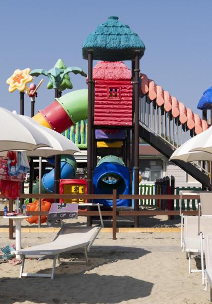Strand mit buntem Spielplatz und weißen Sonnenschirmen.
