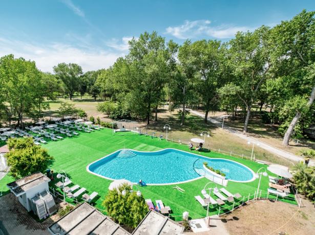 Piscine extérieure entourée de verdure et de transats, nichée dans la nature.