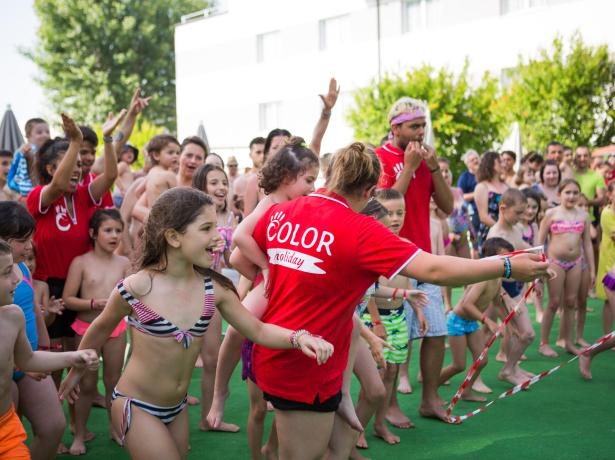 Bambini che giocano all'aperto con animatori in magliette rosse.