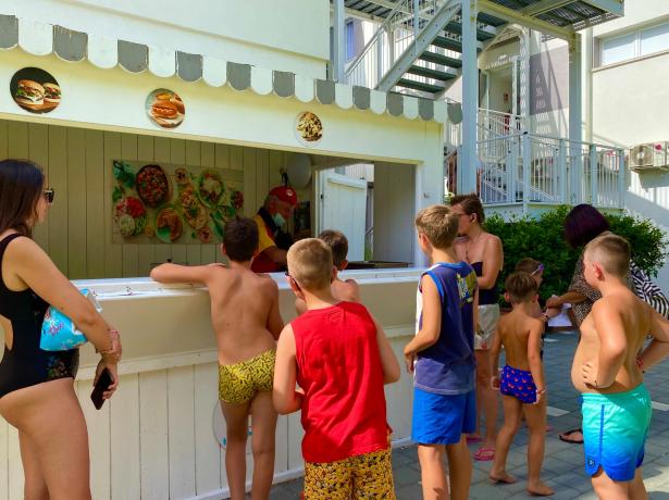 Enfants faisant la queue pour de la nourriture à un kiosque d'été.