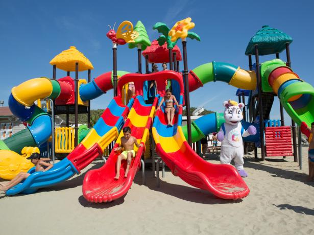 Des enfants jouent sur un toboggan coloré dans une aire de jeux à la plage.