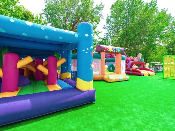 Structures gonflables colorées dans une aire de jeux extérieure avec gazon artificiel.