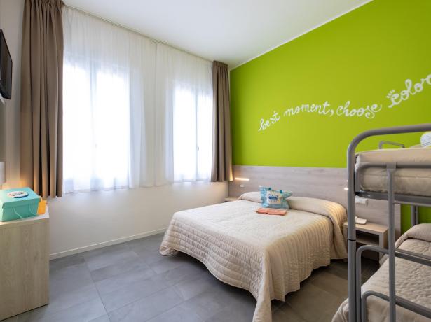 Camera moderna con letto matrimoniale e letti a castello, parete verde brillante.