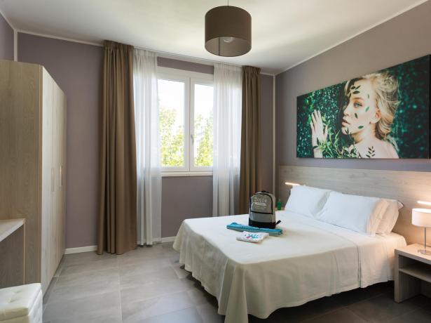 Chambre moderne avec lit double, décoration élégante et fenêtre lumineuse.