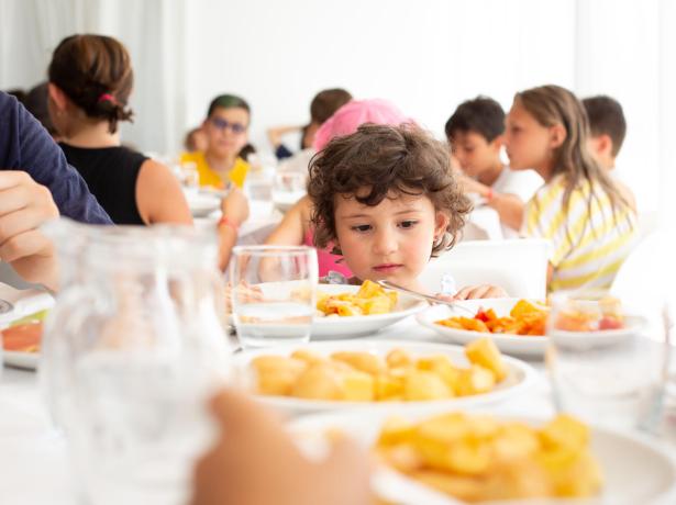 Des enfants mangent ensemble à table, assiettes pleines de nourriture.