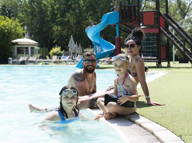 Happy family at the pool with a blue slide.