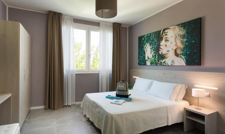 Modernes Zimmer mit Doppelbett, eleganter Dekoration und hellem Fenster.