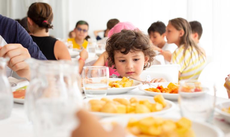 Kinder essen zusammen am Tisch, Teller voller Essen.