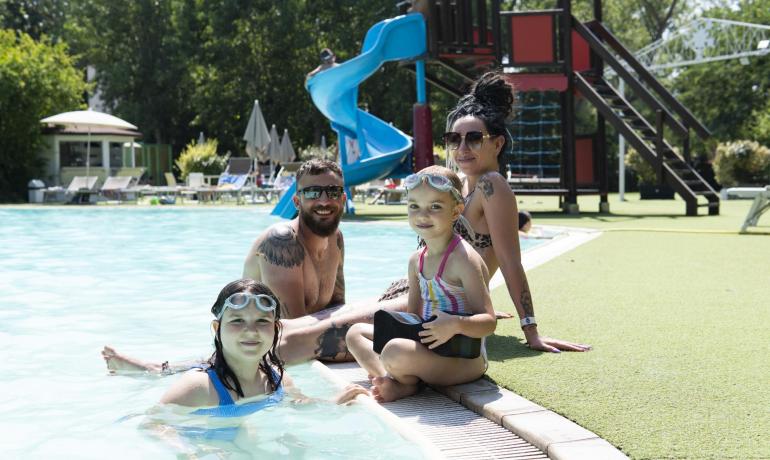 Famiglia felice in piscina con scivolo blu.