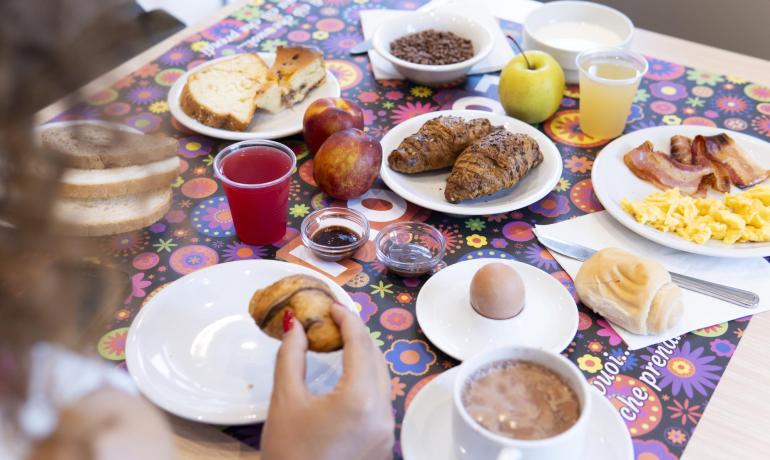 Colazione ricca con croissant, uova, frutta e bevande.
