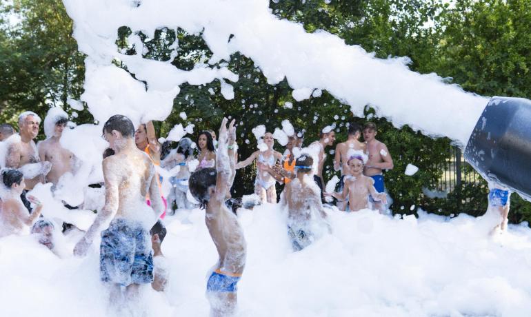 Persone si divertono in una festa di schiuma all'aperto.