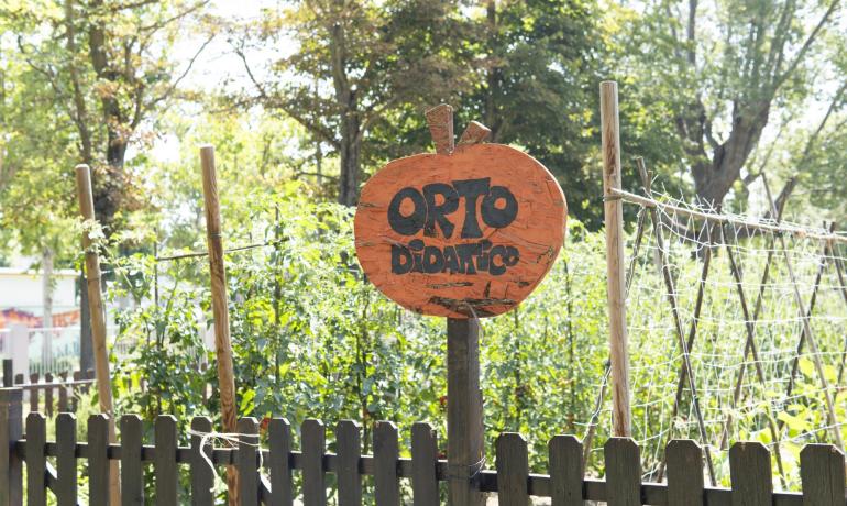 Bildungsgarten mit orangefarbenem Schild in einem sonnigen Garten.