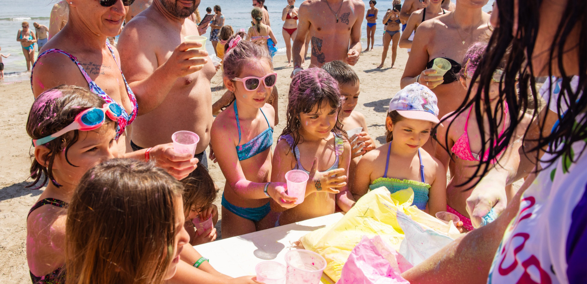 Glückliche Familien spielen mit lebendigen Farben am sonnigen Strand.