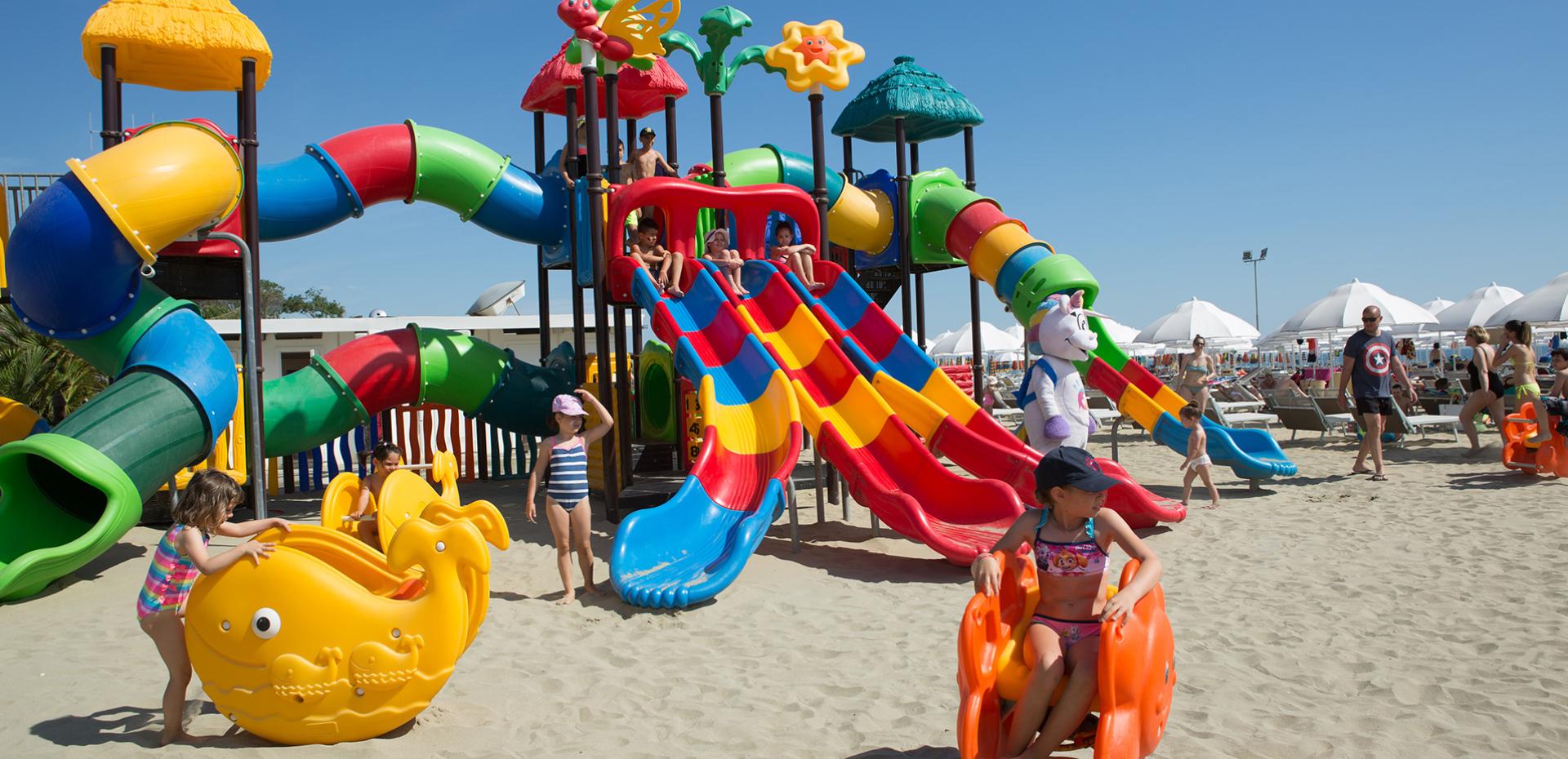 Area giochi per bambini con scivolo giallo e recinto colorato.