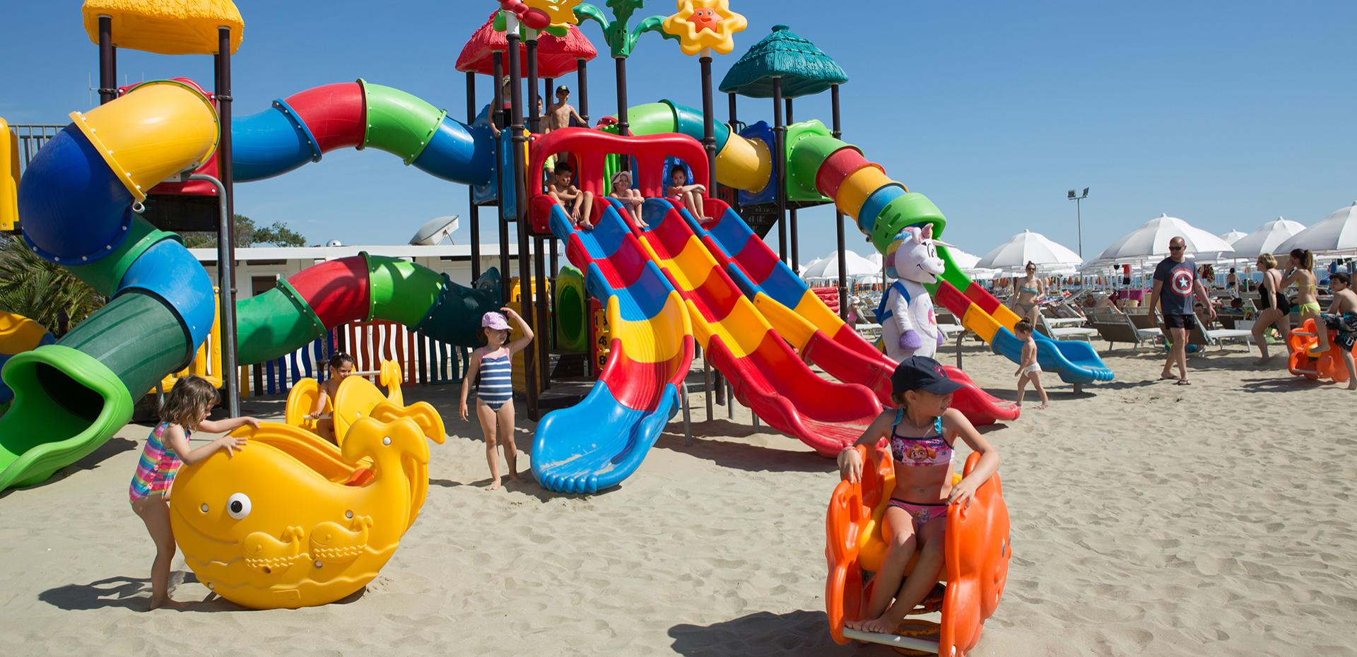 Plage ensoleillée, enfants jouent joyeusement sur des toboggans colorés et manèges.