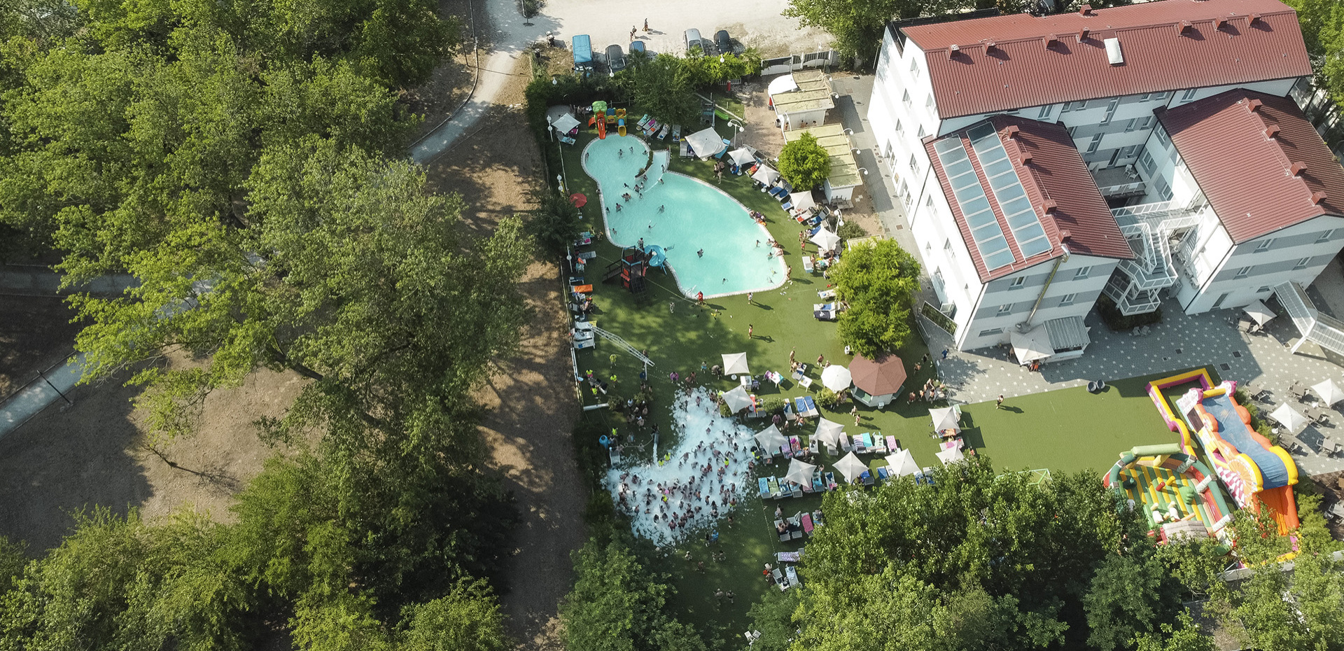 Piscina con giochi acquatici e gonfiabili colorati in un ambiente soleggiato.