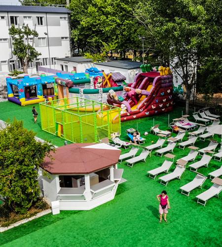 Colorful play area with inflatable slides, sun loungers, umbrellas, lively and joyful atmosphere.