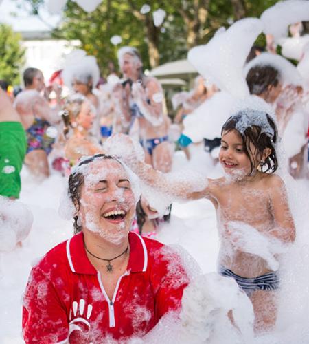 Persone si divertono in una festa di schiuma, immerse in bolle e sorrisi.