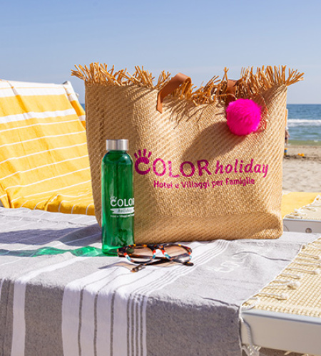 Sunny beach, relaxing on loungers with colorful bag and bottle.