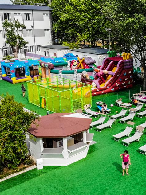 Colorful play area with inflatable slides, sun loungers, umbrellas, lively and joyful atmosphere.