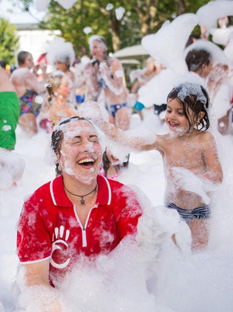 Persone si divertono in una festa di schiuma, immerse in bolle e sorrisi.