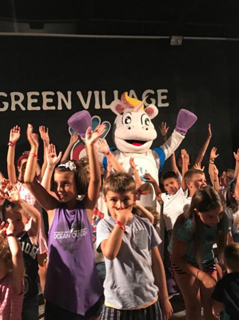 Festa con un costume da unicorno, circondato da bambini felici e sorridenti.
