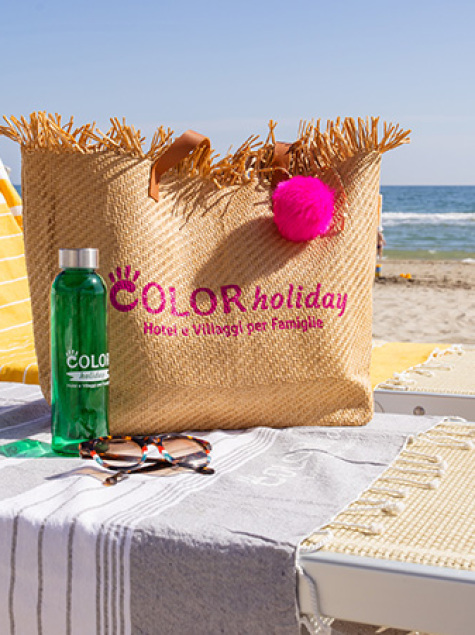 Sunny beach, relaxing on loungers with colorful bag and bottle.
