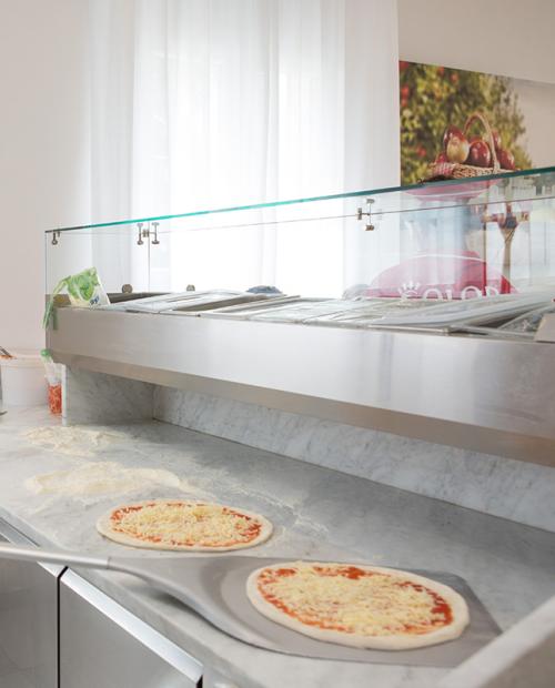 Pizzabäcker bereitet leidenschaftlich Pizzen in heller, einladender Küche zu.