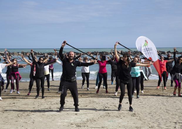 Groupe fait des exercices avec des élastiques sur une plage.